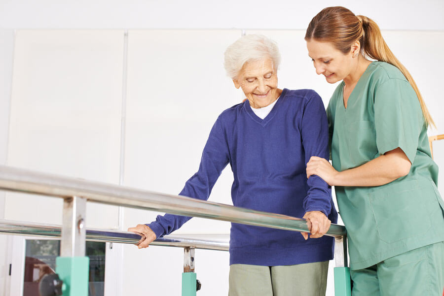 Nurse helping older patient walk during physical therapy.